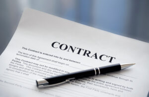 A contract with a pen on top and contract language written.